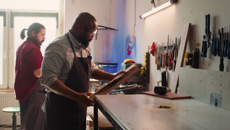 man in woodworking shop inspecting lumber piece before assembling furniture