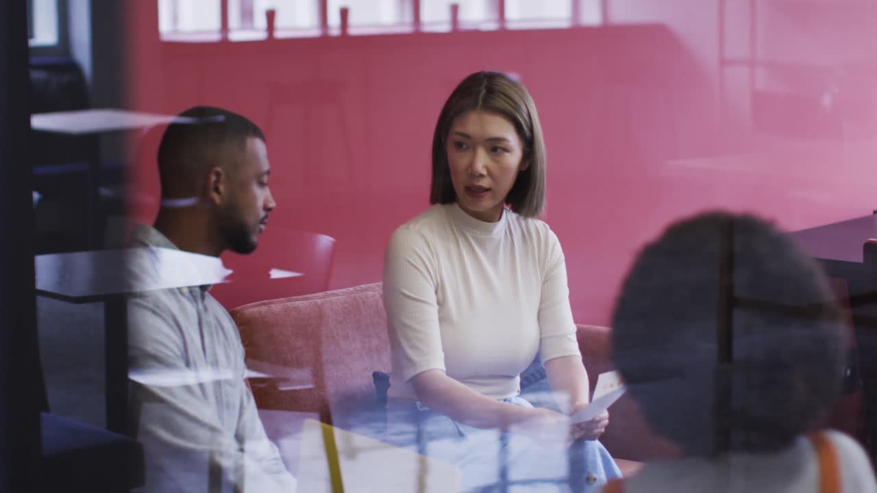 diversas personas de negocios sentadas y hablando pasando por el papeleo en una oficina moderna