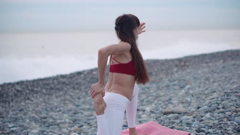 mujer practicando yoga en una playa