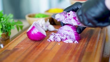 cocinero con guantes cortando cebollas rojas frescas, verduras de tablero de madera cortando comida en cámara lenta