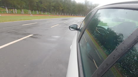 suction cup shot of a white car driving on a wet private course