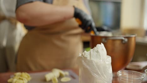 chef using a pastry bag to fill a pastry with whipped cream