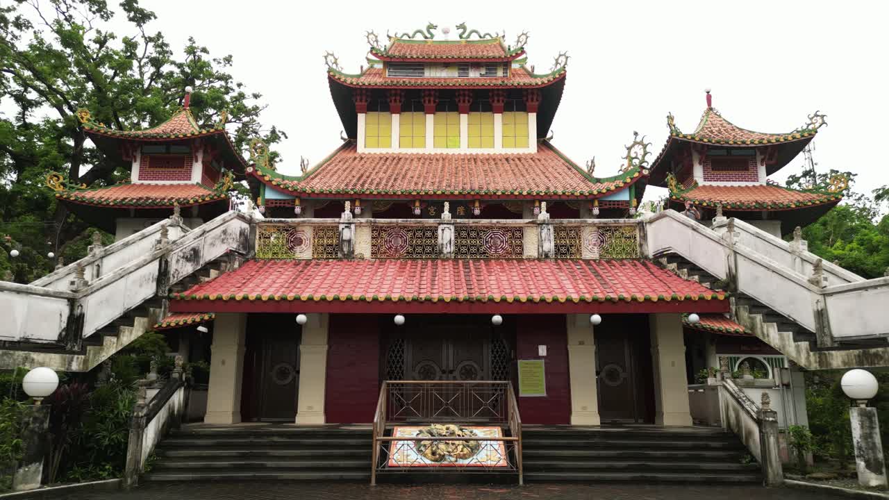 The video opens with aerial and zooming shots of Ma-Cho Temple, revealing its ornate gate, dragon details, staircases, and vibrant façade framed by greenery and an urban backdrop