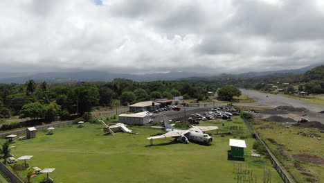 aerial shot of deserted pearls airport in grenada with derelict airplanes among lush greenery, daytime