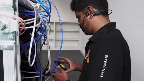 Rising-shot-of-a-hardware-engineer-plugging-in-cables-into-the-back-of-a-server