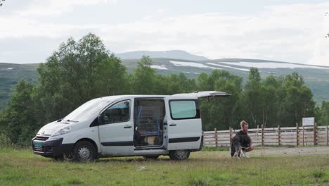 Hombre-Viajero-Y-Su-Perro-Malamute-De-Alaska-Descansando-En-El-Campo-Cerca-De-Trekanten,-Noruega---Tiro-Ancho