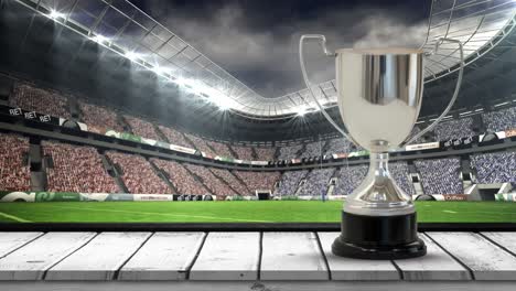 Animation-of-silver-cup-in-rugby-field-with-camera-flashes-in-sports-stadium