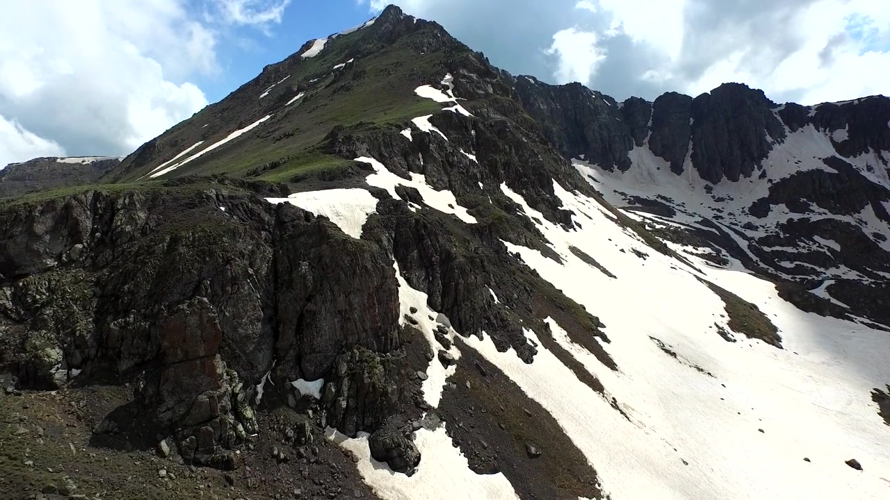 Aerial View of Rugged Mountain Peak with Patches of Snow