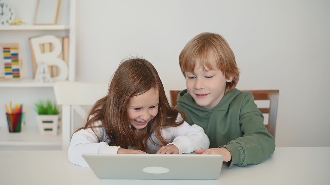 niño y niña usando una computadora portátil y divirtiéndose en casa