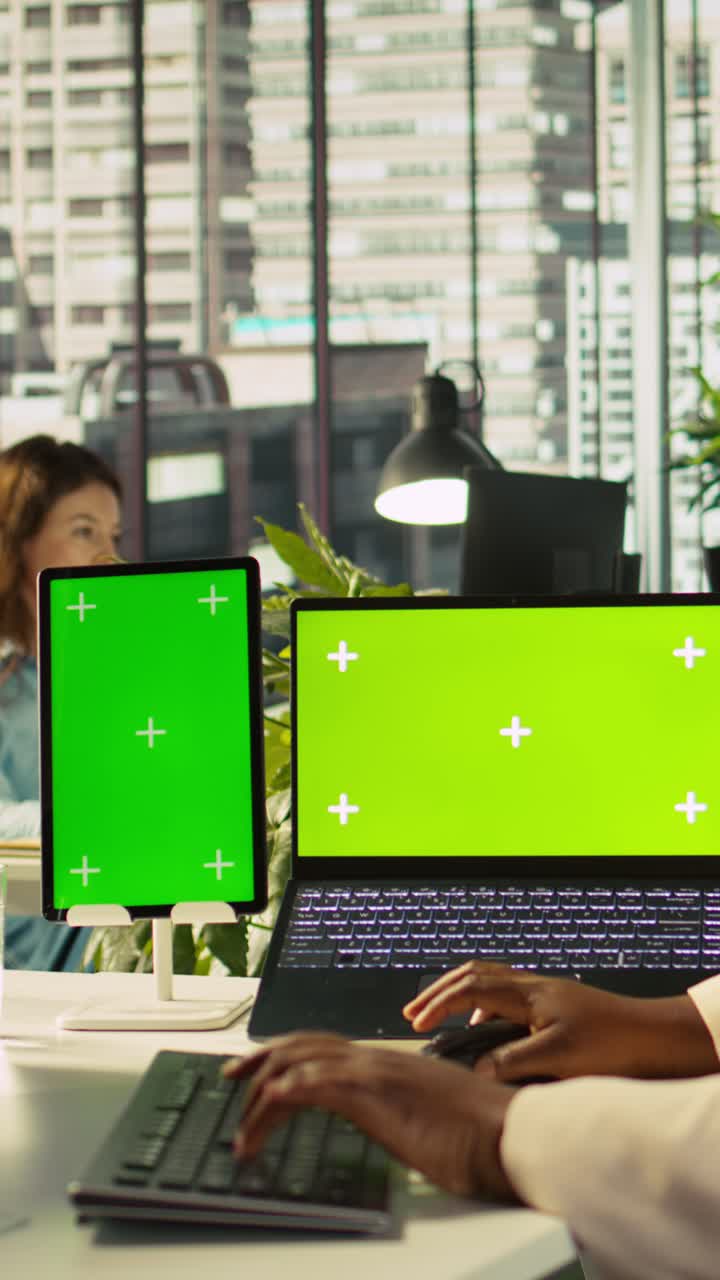 Vertical video Isolated screen devices on office desk next to employee editing documents