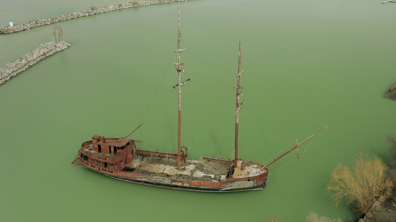 Rusty red shipwreck stuck in shallow green water