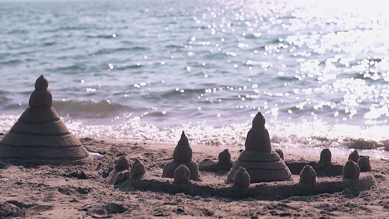 castillo de arena en estilo asiático en la costa y las olas en cámara lenta