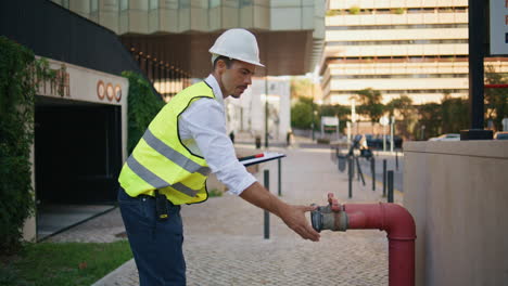 professional man examining pipe making notes at street. expert writing review