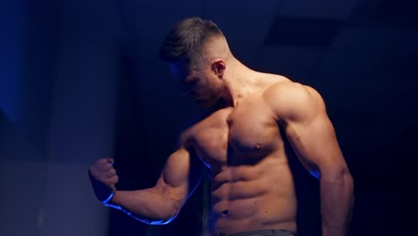 man posing in gym. handsome mature man standing strong in the gym and flexing muscles