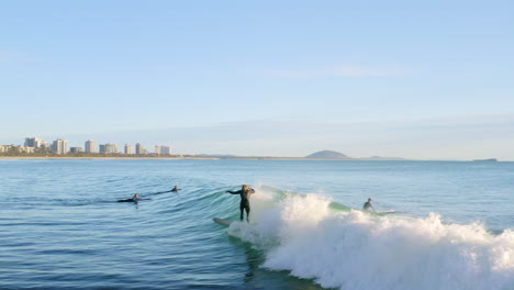 surfer dropping in and surfing barrel in ocean waves off australian beach, 4k aerial drone