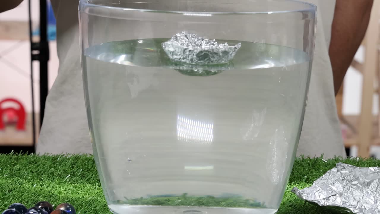 Experiment with foil boats and marbles to observe buoyancy and sinking in water.