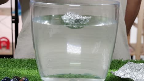experiment with foil boats and marbles to observe buoyancy and sinking in water.