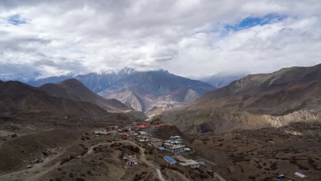 un video de lapso de tiempo de nubes moviéndose sobre las escarpadas montañas del himalaya con la ciudad de muktinath en primer plano