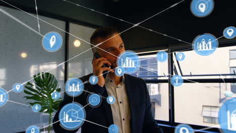 network of digital icons against caucasian businessman talking on smartphone at office
