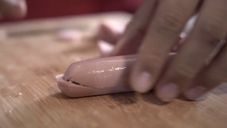 chico cortando salchichas en una tabla de madera