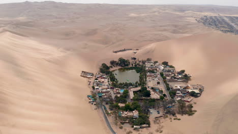 vista aérea sobre el pequeño pueblo de huacachina peru, un pequeño pueblo alrededor de un oasis en el desierto rodeado de dunas de arena