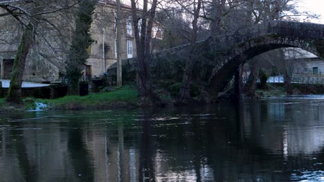 reflection of banos de molgas city in river with roman bridge