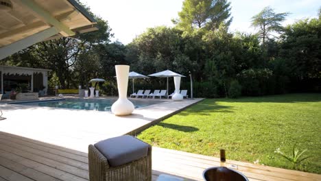 slow establishing shot of garden furniture sat around a villas swimming pool