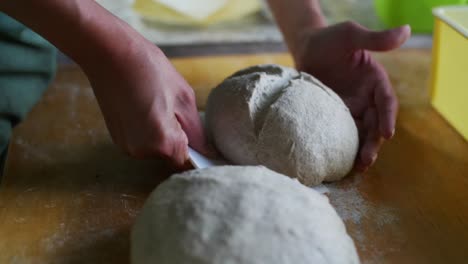 fully prepared dough ball ready for baking lifted up using scraping tool, filmed as close up in slow motion style