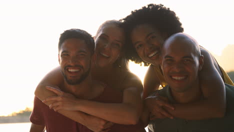 outdoor portrait of friends in countryside with men giving women piggybacks