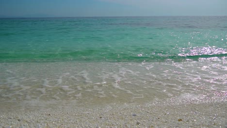 Slow-Motion-Of-Crystal-Clear-Turquoise-Sea-Waves-Splashing-On-Marble-Beach,-Clear-Blue-Sky-In-The-Background,-White-Beach,-Thassos-Island,-Greece