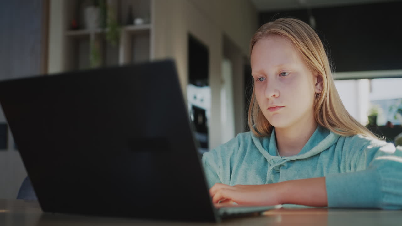un niño usa una computadora portátil en la cocina de su casa. concepto de aprendizaje a distancia