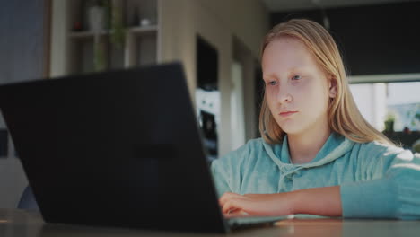 a child uses a laptop in the kitchen of his home. distance learning concept