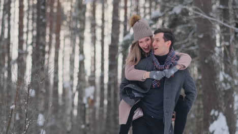 Happy-Couple-is-Playing-Winter-Game-Outside-Enjoying-Sunlight-and-Warm-Winter-Weather-in-the-Mountains.-Strong-Boy-is-Carrying-Girlfriend-on-His-Shoulders-and-Whirls-Her