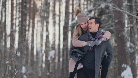 Una-Pareja-Feliz-Está-Jugando-Juegos-De-Invierno-Afuera-Disfrutando-De-La-Luz-Del-Sol-Y-Del-Cálido-Clima-Invernal-En-Las-Montañas.-Un-Chico-Fuerte-Lleva-A-Su-Novia-Sobre-Sus-Hombros-Y-La-Hace-Girar.