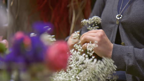 skilled florist cutting flower in preparation for flower bouquet