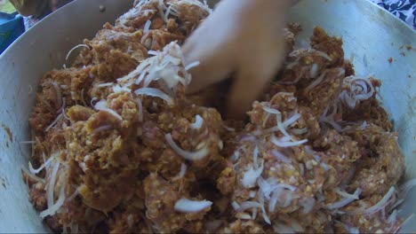 mince meat, onions and spices in casserole pan being kneaded