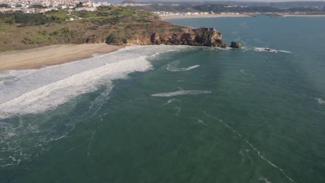 Luftaufnahme-Des-Atlantischen-Ozeans-Mit-Schnellbooten,-Die-über-Das-Wasser-Fahren,-Und-Der-Küste-Des-Strandes-Von-Nazare