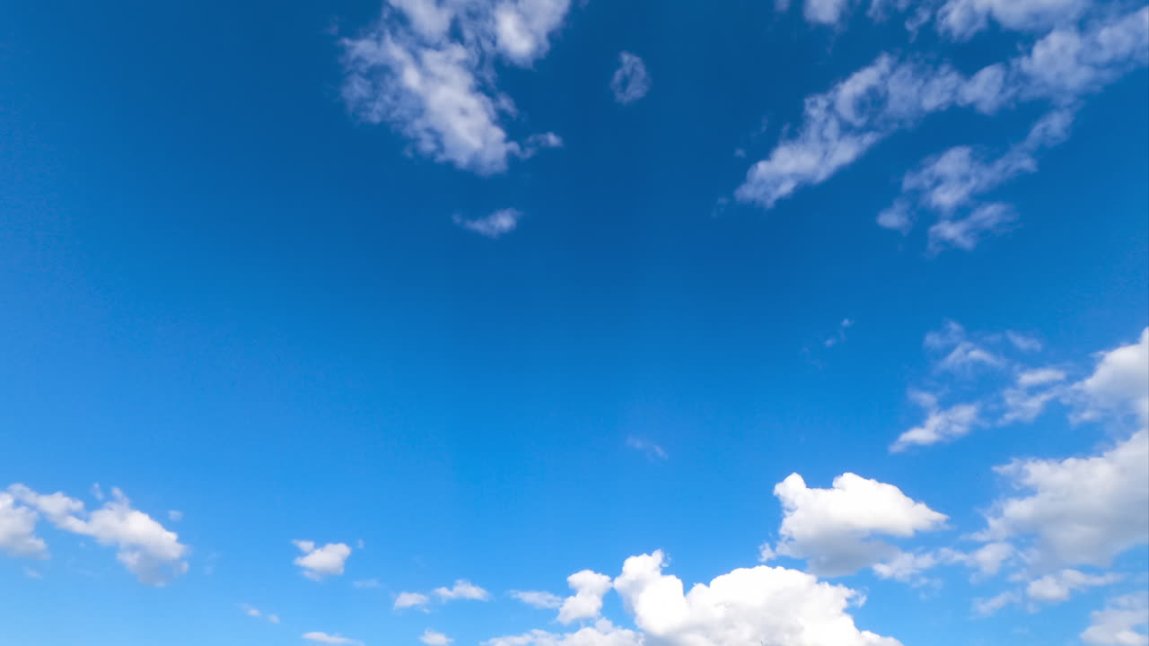 Light airy clouds moving along the blue sky. Beautiful white fluffy clouds against bright sky. Timelapse.