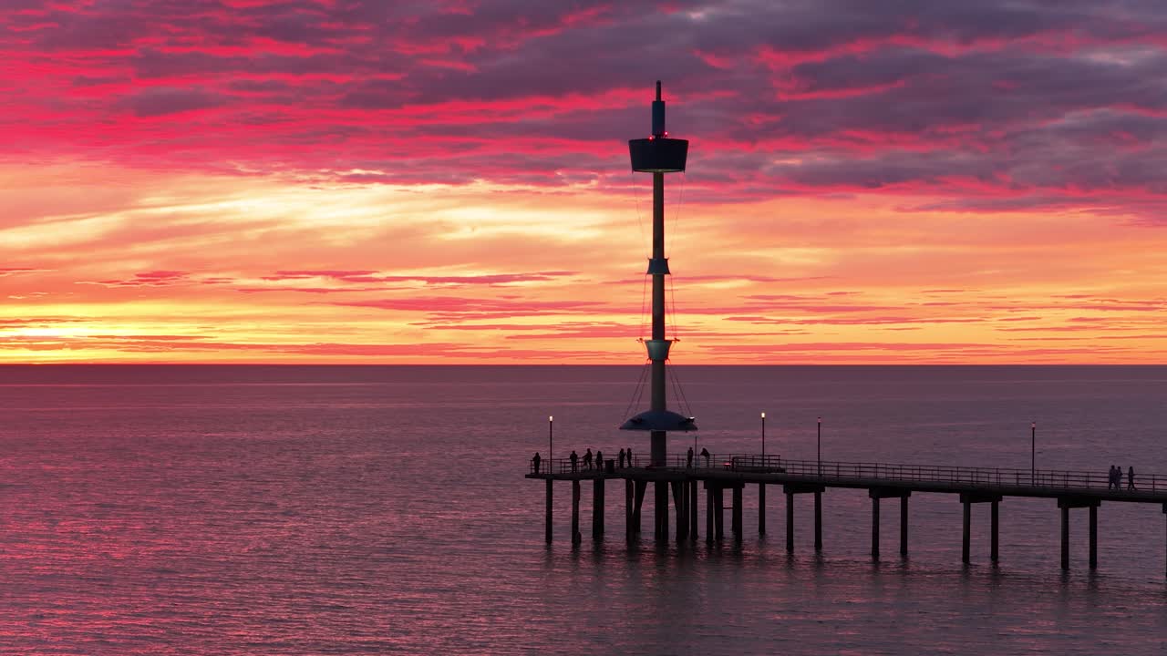 Aerial shot of Brighton Beach jetty silhouette with vibrant red and orange sunset cloud color in Adelaide, South Australia