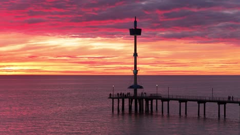 aerial shot of brighton beach jetty silhouette with vibrant red and orange sunset cloud color in adelaide, south australia