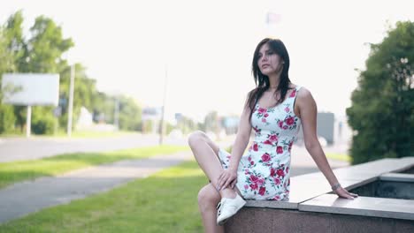 round-motion-long-haired-brunette-girl-sits-on-grey-parapet