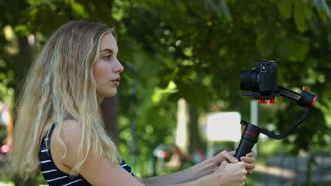 a cool lady standing outside, record herself singing with a camera and taking different pose for the picture