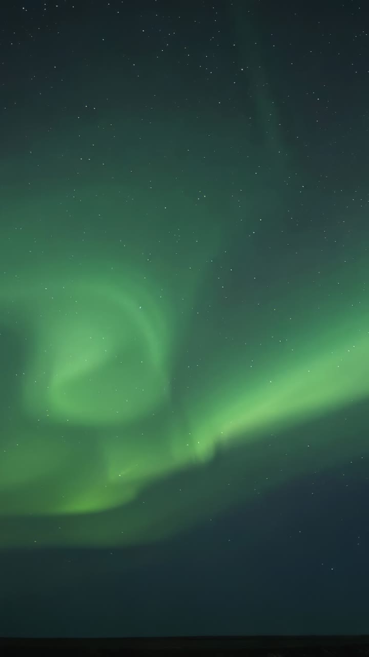 Vertical video: Dancing aurora spiral with curtains shifting over horizon, reacting to solar wind