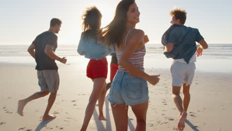 group of friends running towards ocean on beach vacation