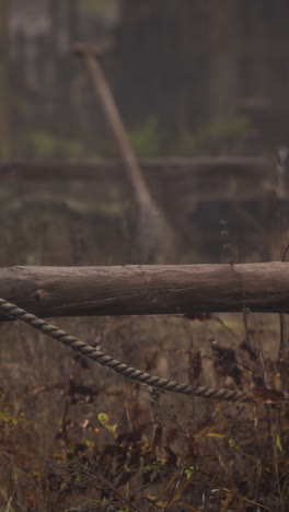 una cuerda colgando de una vieja valla de madera en un campo de niebla