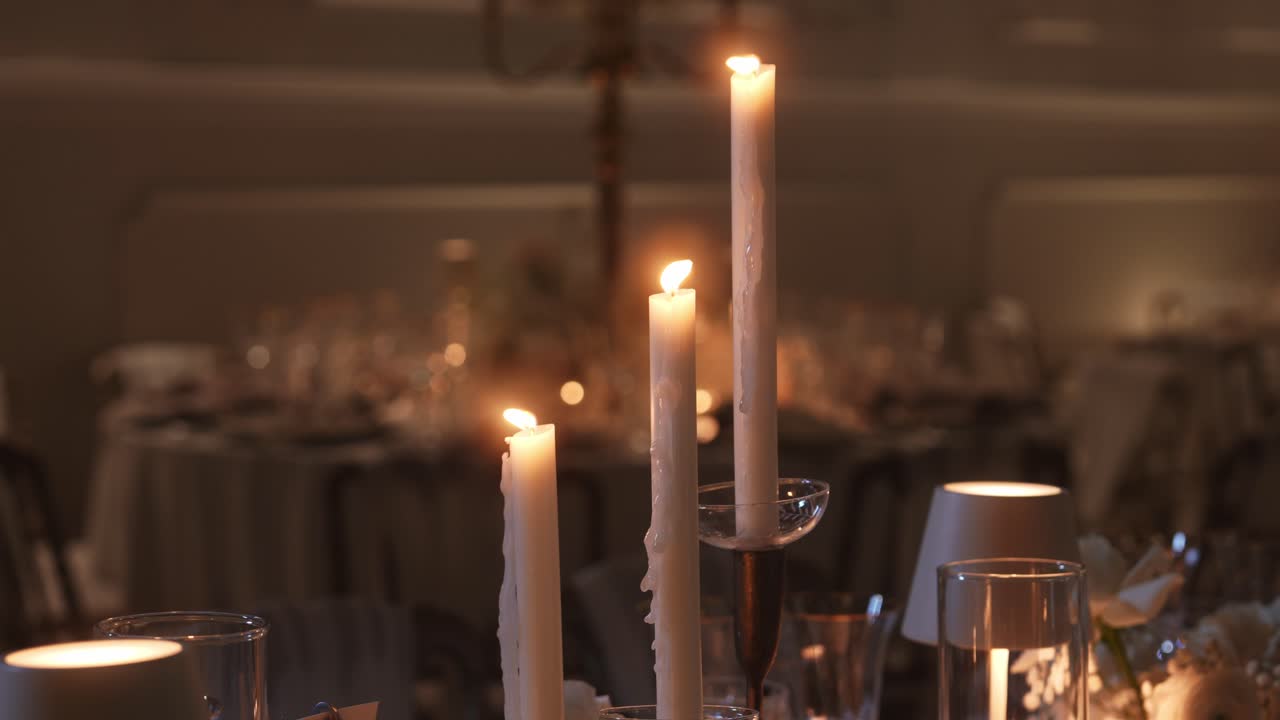 Candele accese e cristalleria su un tavolo da pranzo in interni.