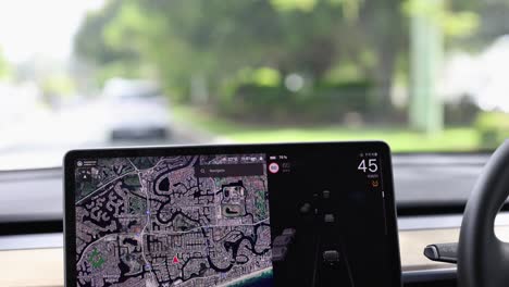 a car navigates gold coast streets using a digital map display. bright daylight illuminates the lush surroundings