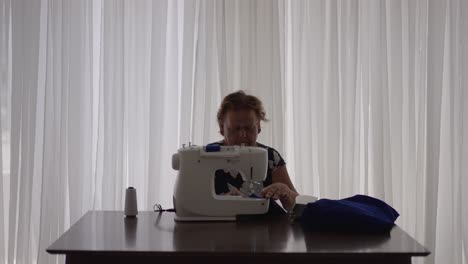 sastre usando máquina de coser para hacer vestido azul