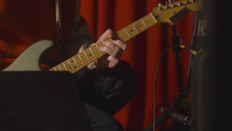 Close-Up-Of-An-Unrecognizable-Musician-With-Electric-Guitar-Tuning-Sound-On-Amplifier