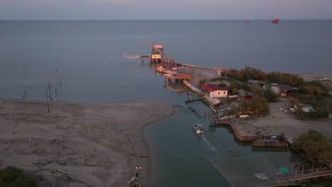 Luftaufnahme-Von-Fischerhütten-Am-Ufer-Der-Mündung-Bei-Sonnenuntergang,-Italienische-Fischermaschine,-Genannt-&quot;Trabucco&quot;,-Lido-Di-Dante,-Ravenna-In-Der-Nähe-Des-Comacchio-Tals